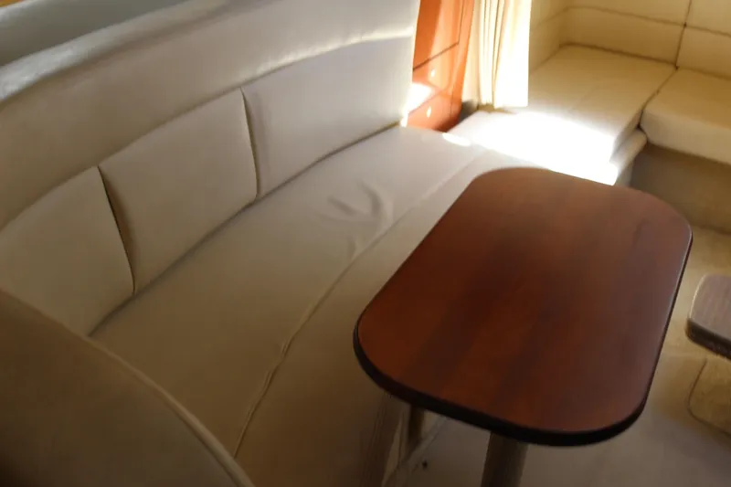Slide: The Image of Interior of 2005 Sea Ray 300 Sundancer with beige seating and wooden table. - 19
