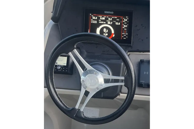 Slide: The Image of 2022 Premier Solaris 230 boat interior with white seating, docked near jet skis. - 14