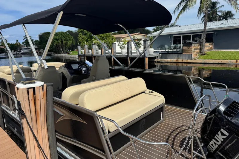 Slide: The Image of 2022 Premier Solaris 230 pontoon boat docked by a scenic waterway. - 2