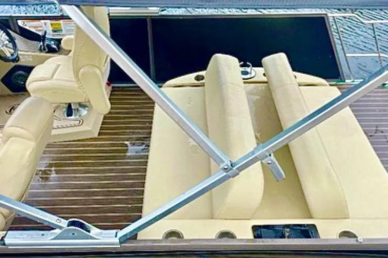 Slide: The Image of Premier Solaris 230 pontoon boat docked by a canal, surrounded by palm trees. - 5