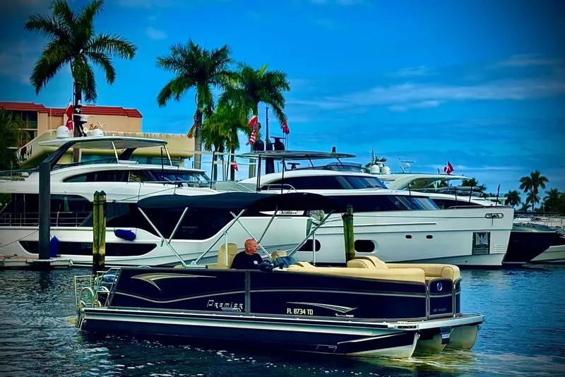Slide: The Image of 2022 Premier Solaris 230 pontoon boat cruising in a marina with yachts and palm trees. - 73