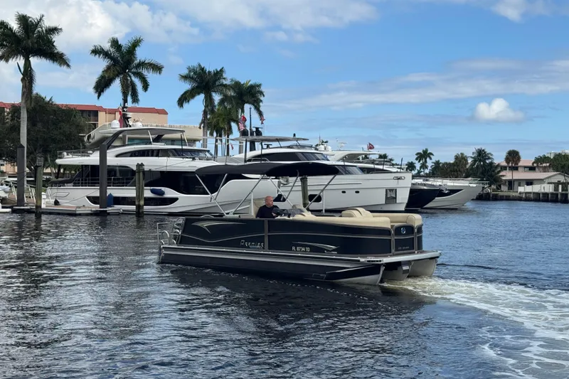Slide: The Image of 2022 Premier Solaris 230 pontoon boat cruising near luxury yachts and palm trees. - 74