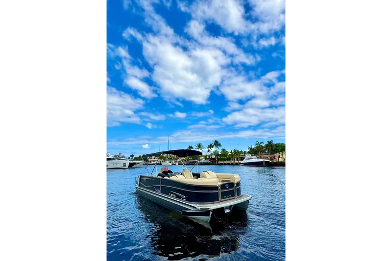 Slide: The Image of 2022 Premier Solaris 230 pontoon boat on a sunny day, with blue sky and palm trees. - 77