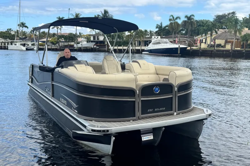 Slide: The Image of 2022 Premier Solaris 230 pontoon boat on a calm waterway, featuring luxurious seating and canopy. - 79
