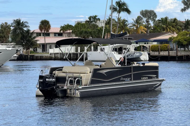 Slide: The Image of 2022 Premier Solaris 230 pontoon boat on water, surrounded by palm trees and waterfront homes. - 82