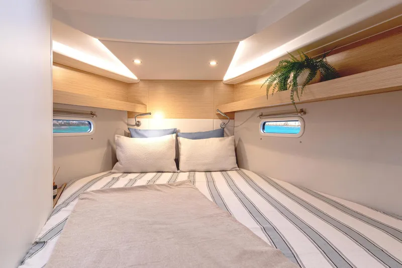 Slide: The Image of Cozy cabin interior of 2025 Hanse 360 yacht with striped bedding and porthole windows. - 27