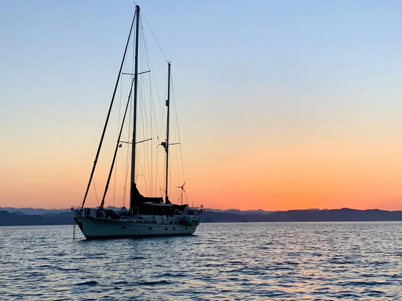 Slide: The Image of Sailboat Aleutian 51 (1977) at sunset on calm sea with distant mountains. - 11