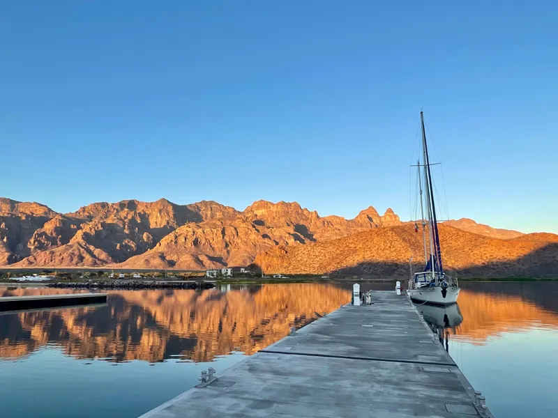 Slide: The Image of Sailboat docked by serene lake with mountain reflections, Aleutian 51, 1977 model. - 13