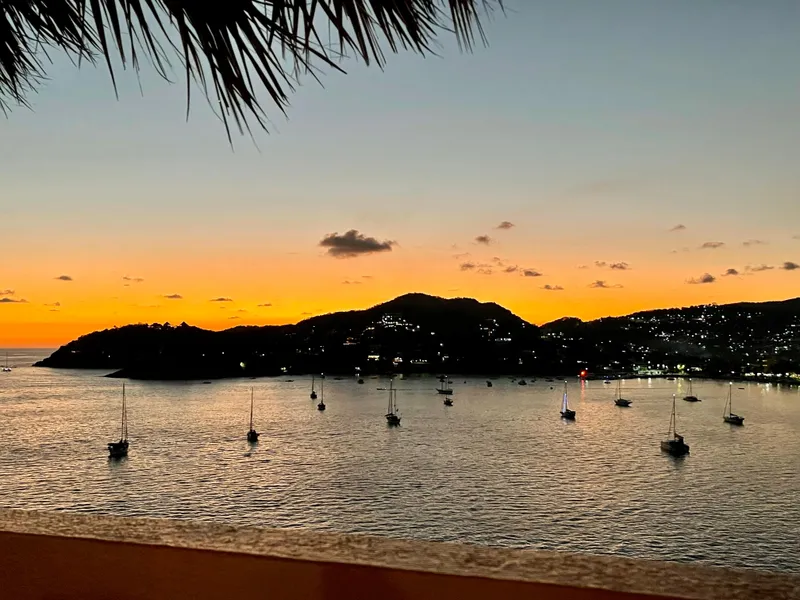 Slide: The Image of Sunset over a tranquil bay with sailboats, silhouetted hills, and a vibrant sky. - 38