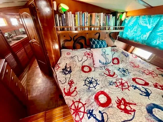 Slide: The Image of Cozy 1977 Aleutian 51 yacht cabin with nautical-themed bedding and bookshelf. - 48