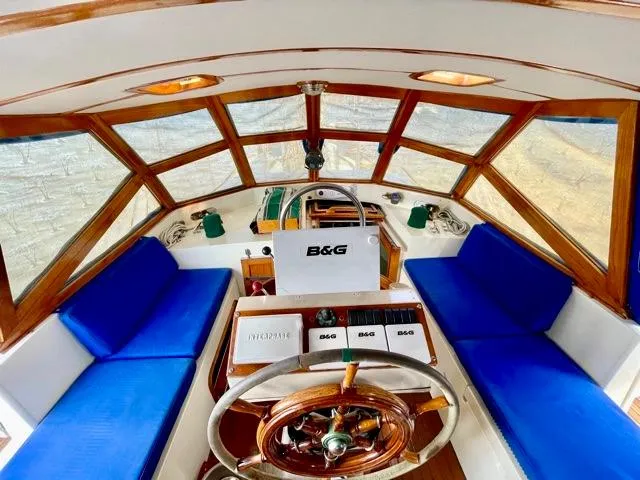 Slide: The Image of 1977 Aleutian 51 yacht interior with blue seating and wooden steering wheel. - 7