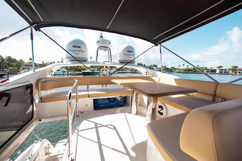 Slide: The Image of Luxurious 2015 Absolute 56 FLY yacht flybridge with seating and table, overlooking serene waterfront. - 1