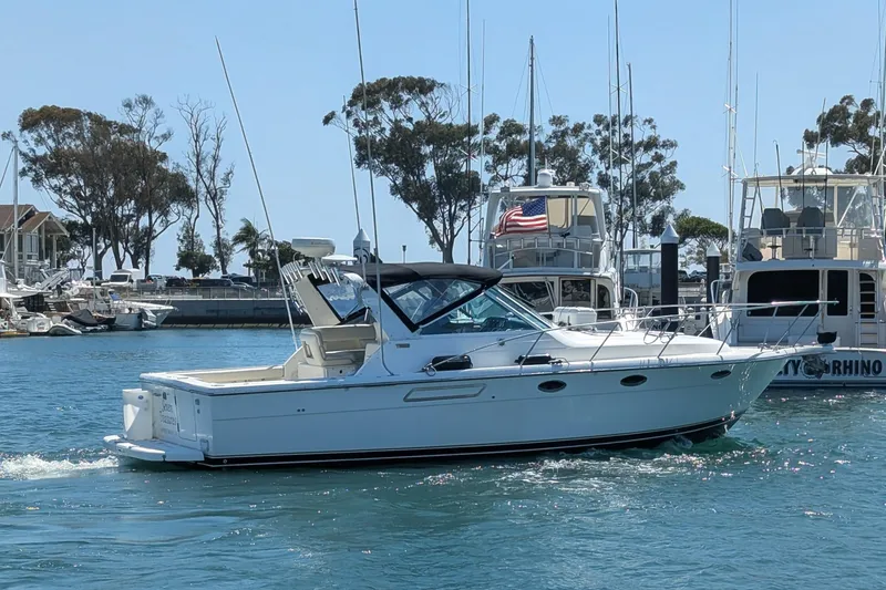 Slide: The Image of 1995 Tiara Yachts 3100 Open cruising in a marina, surrounded by boats and trees. - 15