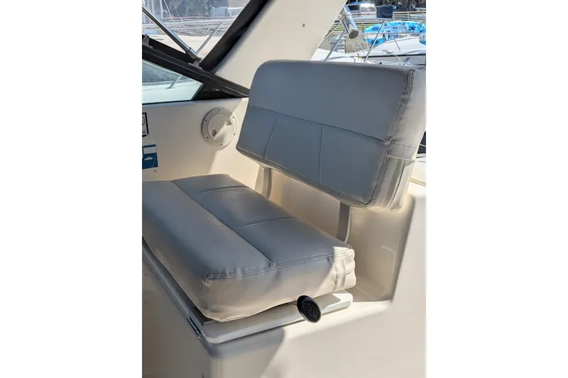 Slide: The Image of 1995 Tiara Yachts 3100 Open boat seat with gray upholstery and window view. - 25