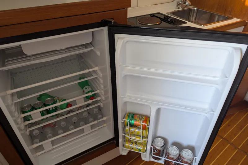 Slide: The Image of Open fridge in 1995 Tiara Yachts 3100 Open, stocked with drinks and water bottles. - 35