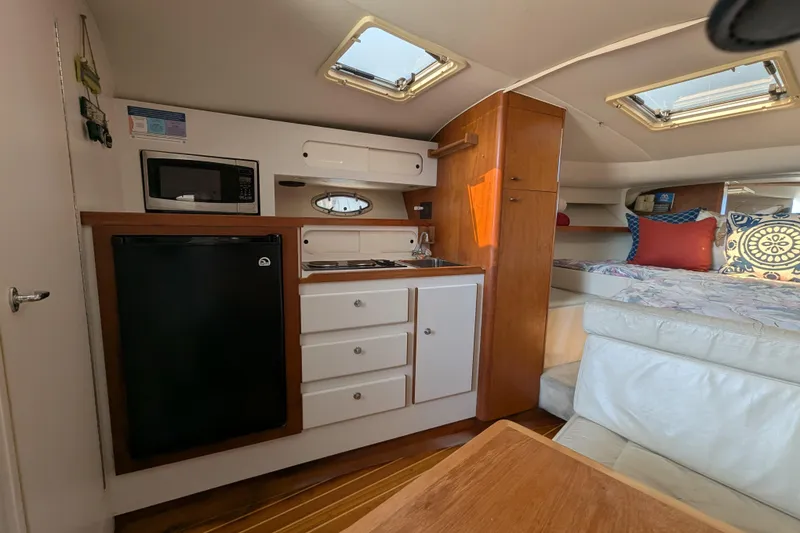 Slide: The Image of Interior of 1995 Tiara Yachts 3100 Open, featuring kitchenette and cozy sleeping area. - 36