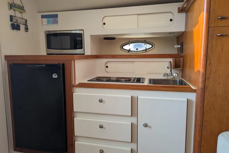 Slide: The Image of 1995 Tiara Yachts 3100 Open galley with microwave, stove, sink, and refrigerator. - 38