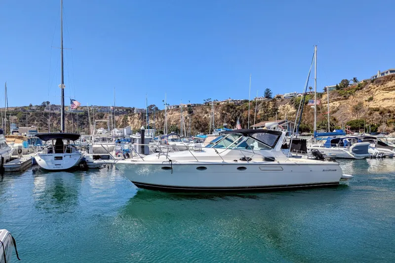 Slide: The Image of 1995 Tiara Yachts 3100 Open docked in a scenic marina under clear blue skies. - 5