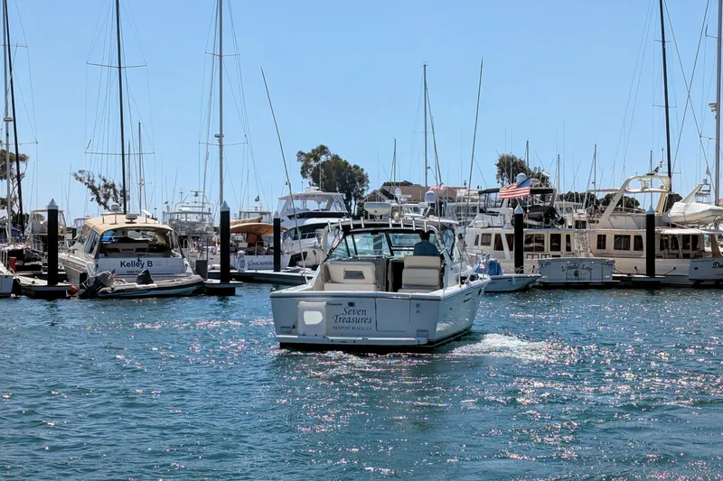 Slide: The Image of 1995 Tiara Yachts 3100 Open cruising in a marina with other boats docked nearby. - 6