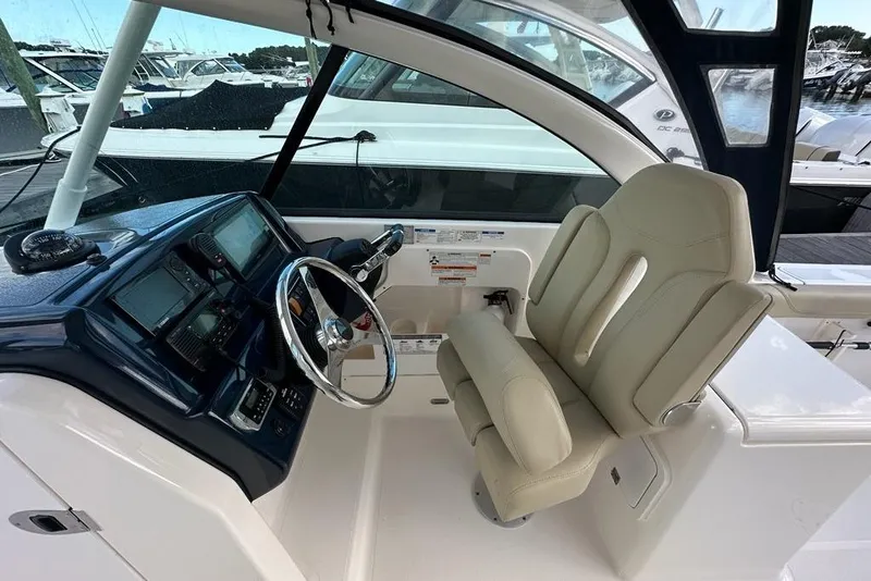 Slide: The Image of Interior of a 2016 Pursuit DC 265 Dual Console boat with steering wheel and captain's chair. - 14