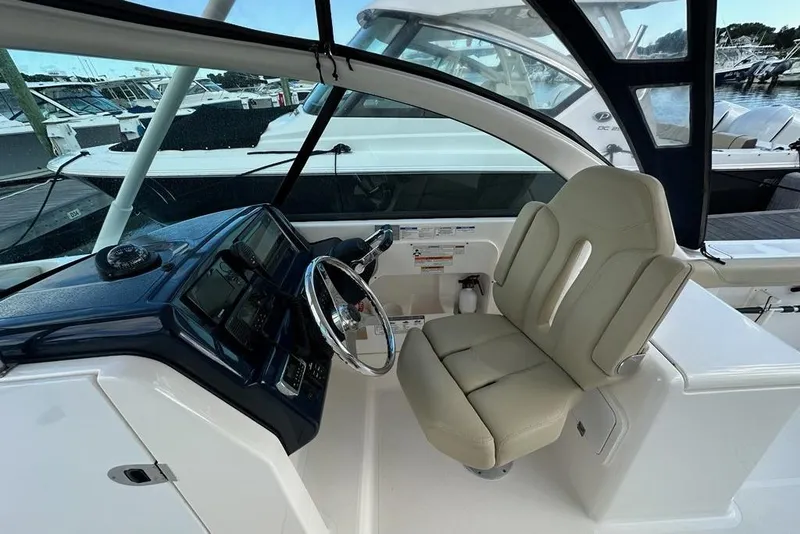Slide: The Image of 2016 Pursuit DC 265 Dual Console boat interior with steering wheel and beige captain's chair. - 15