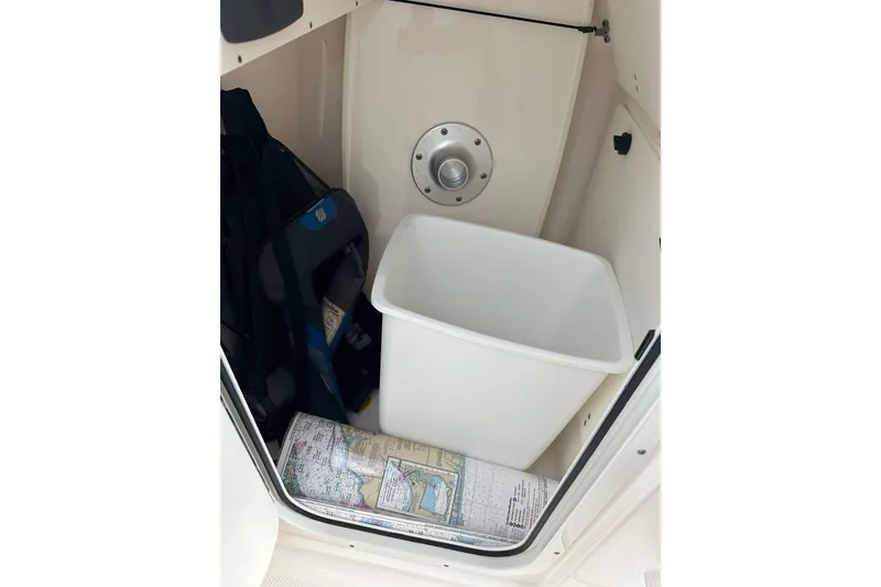 Slide: The Image of Storage compartment in a 2016 Pursuit DC 265 Dual Console boat with a map and bin. - 18