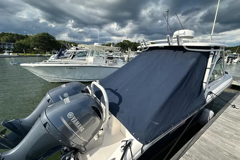 Slide: The Image of 2016 Pursuit DC 265 Dual Console boat docked with Yamaha engines, under cloudy skies. - 2