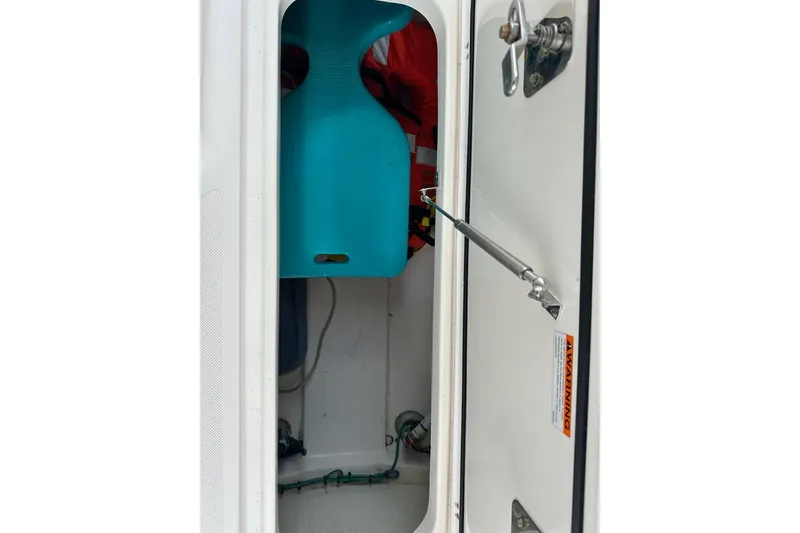 Slide: The Image of Storage compartment of a 2016 Pursuit DC 265 Dual Console boat, featuring safety equipment. - 24