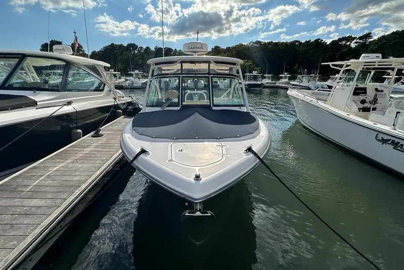 Slide: The Image of 2016 Pursuit DC 265 Dual Console boat docked in a marina under a partly cloudy sky. - 3