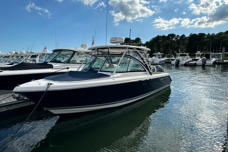 Slide: The Image of 2016 Pursuit DC 265 Dual Console boat docked in a marina under a blue sky. - 4