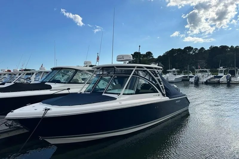 Slide: The Image of 2016 Pursuit DC 265 Dual Console boat docked in a marina under a clear blue sky. - 5