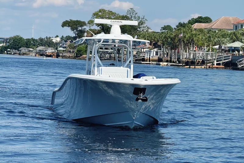 Slide: The Image of 2024 Yellowfin 34 Offshore boat cruising on a scenic waterway with lush greenery. - 2