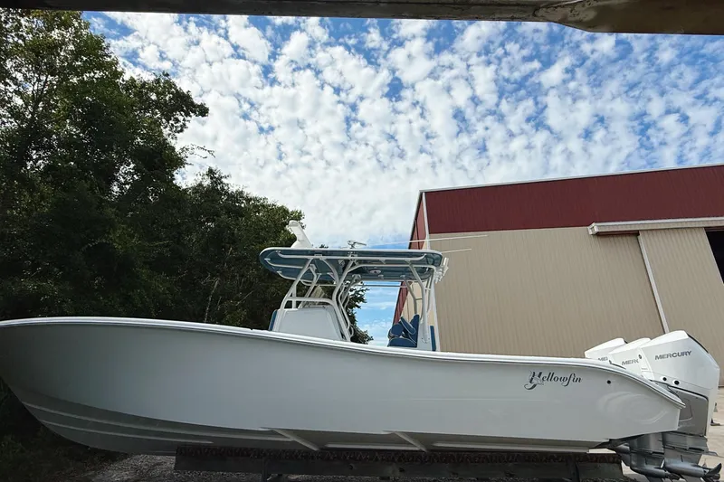 Slide: The Image of 2024 Yellowfin 34 Offshore boat on calm water, with coastal buildings in the background. - 3