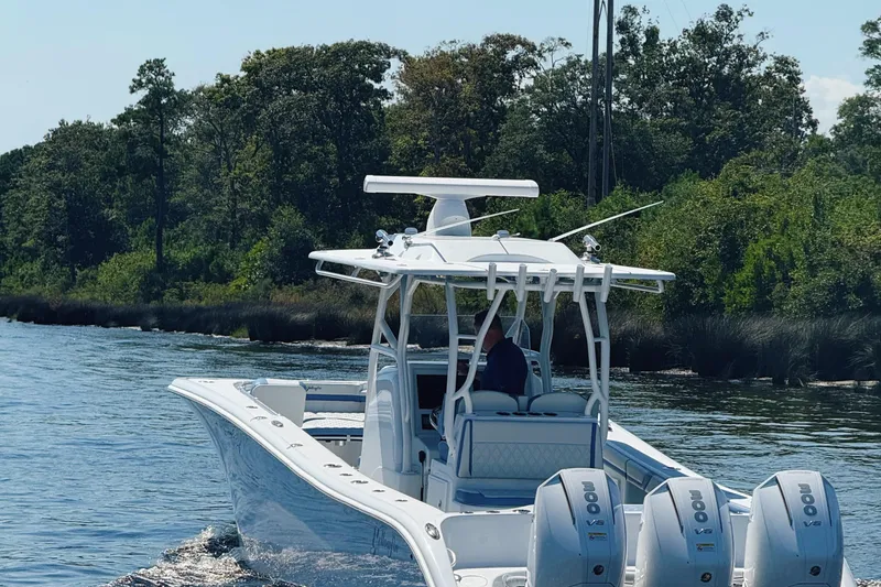 Slide: The Image of 2024 Yellowfin 34 Offshore boat cruising on a calm river with lush greenery. - 4