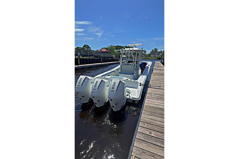 Slide: The Image of 2024 Yellowfin 34 Offshore boat interior with blue and white seating, surrounded by trees. - 7