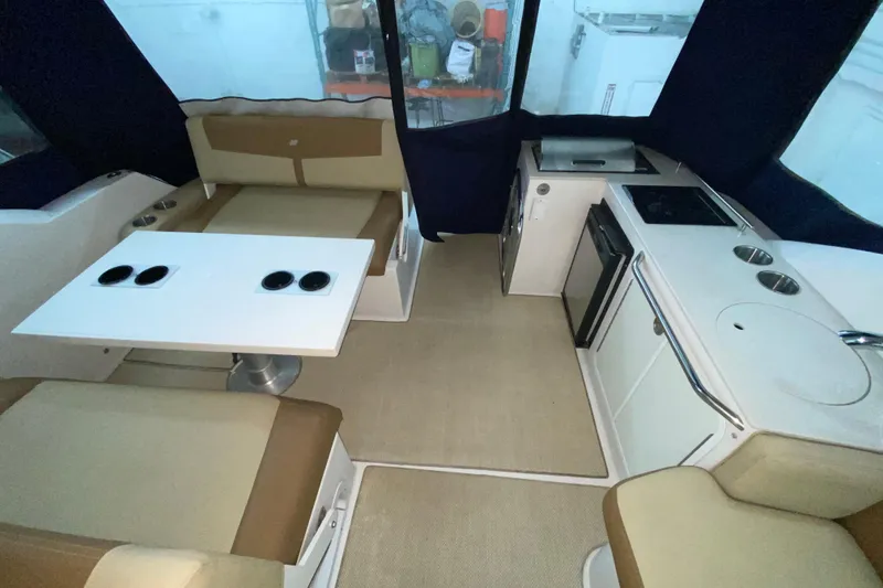Slide: The Image of 2012 Four Winns V305 boat interior with seating, table, and kitchenette. - 18