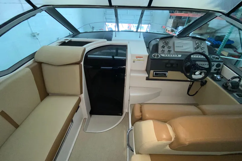 Slide: The Image of Interior of 2012 Four Winns V305 boat with beige seating and modern dashboard. - 23
