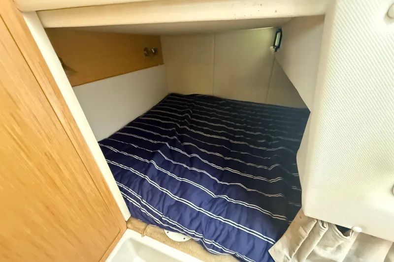 Slide: The Image of 2012 Four Winns V305 cabin interior with striped bedding, cozy sleeping area. - 26