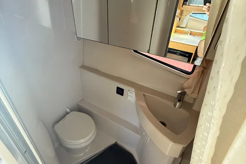 Slide: The Image of 2012 Four Winns V305 boat bathroom with toilet, sink, and mirror cabinet. - 27