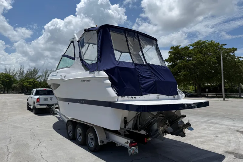 Slide: The Image of 2012 Four Winns V305 boat on trailer, parked outdoors under a cloudy sky. - 28