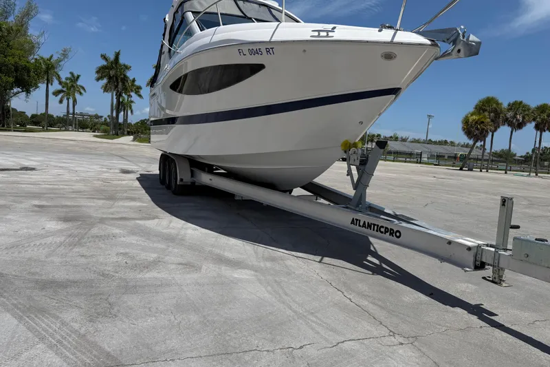 Slide: The Image of 2012 Four Winns V305 boat on trailer in sunny parking lot. - 3