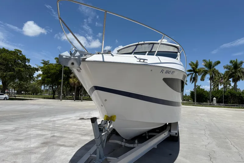 Slide: The Image of 2012 Four Winns V305 boat on trailer, parked under clear blue sky. - 4