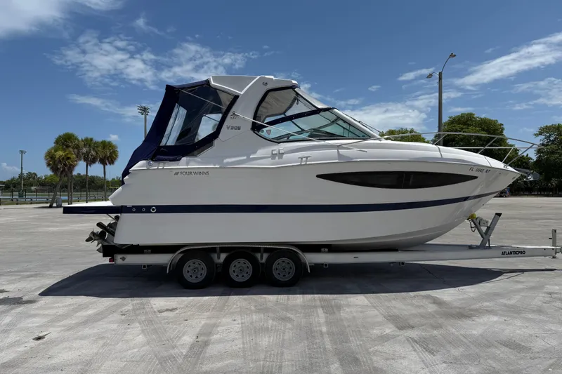 Slide: The Image of 2012 Four Winns V305 boat on trailer, parked outdoors under a clear blue sky. - 5
