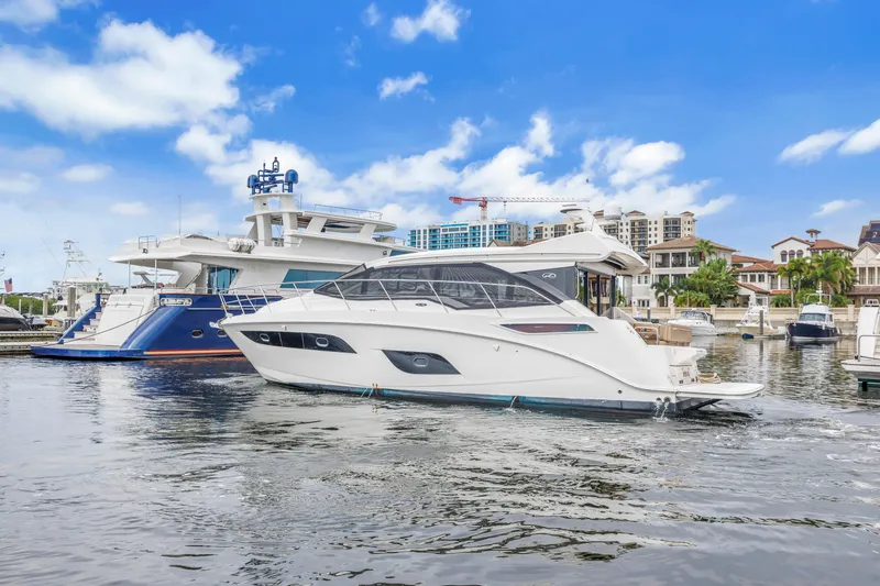Slide: The Image of 2017 Sea Ray Sundancer 460 yacht docked in a marina, under a clear blue sky. - 2