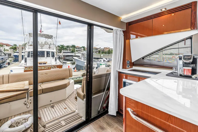 Slide: The Image of Interior view of 2017 Sea Ray Sundancer 460 yacht with modern kitchen and marina backdrop. - 25