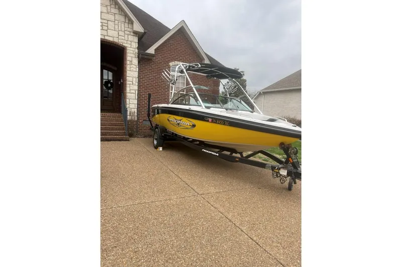 Slide: The Image of 2008 Moomba Mobius LSV boat in driveway, yellow and black design, near brick house. - 2