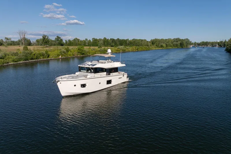Slide: The Image of 2018 Cranchi Eco Trawler 53 Long Distance cruising on a serene river under a clear blue sky. - 11