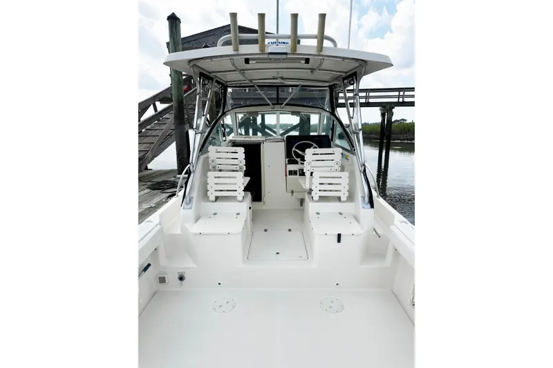 Slide: The Image of 2005 Pursuit 2870 Walkaround boat interior with seating and steering wheel, docked by water. - 11