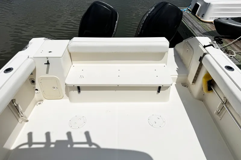 Slide: The Image of 2005 Pursuit 2870 Walkaround boat interior with seating and storage, docked by the water. - 14