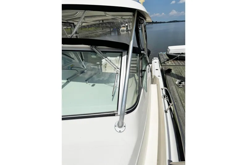 Slide: The Image of 2005 Pursuit 2870 Walkaround boat docked by a calm lake. - 23